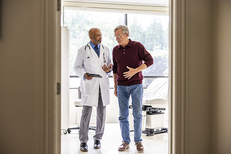 Male doctor with male patient holding his stomach