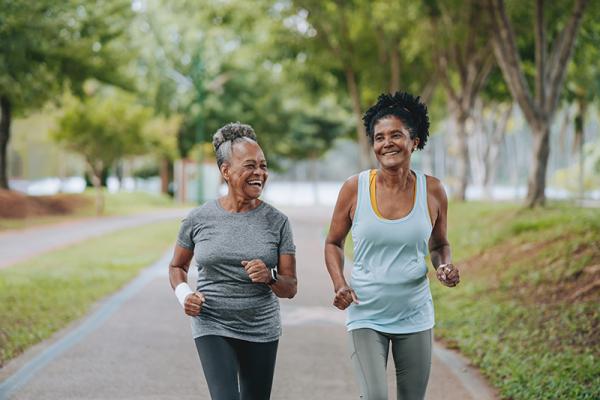 Two women jogging on a tree-lined path