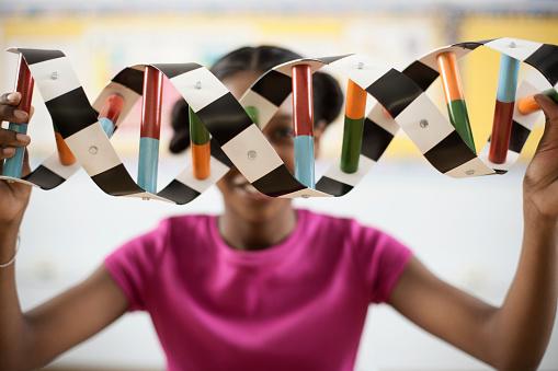 Woman holding a double-helix model between her spread arms